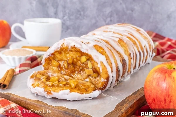 Apple Cinnamon Pull Apart Bread - homemade apple pie filling inside layers of bread dough bake into a gooey pull apart bread. Make this homemade recipe for breakfast or brunch this fall. A loaf of apple cinnamon pull apart bread drizzled with glaze on a wood tray