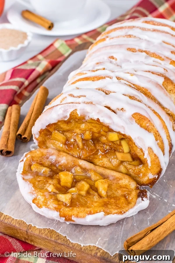 Apple Cinnamon Pull Apart Bread - homemade apple pie filling inside layers of bread dough bake into a gooey pull apart bread. Make this homemade recipe for breakfast or brunch this fall. A slice of apple cinnamon pull apart bread lying on a wood board with the rest of the loaf behind it
