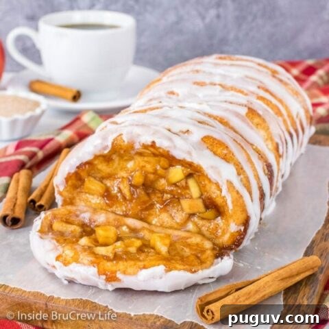 A loaf of apple cinnamon pull apart bread on a wood tray with a slice lying down showing the apple filling