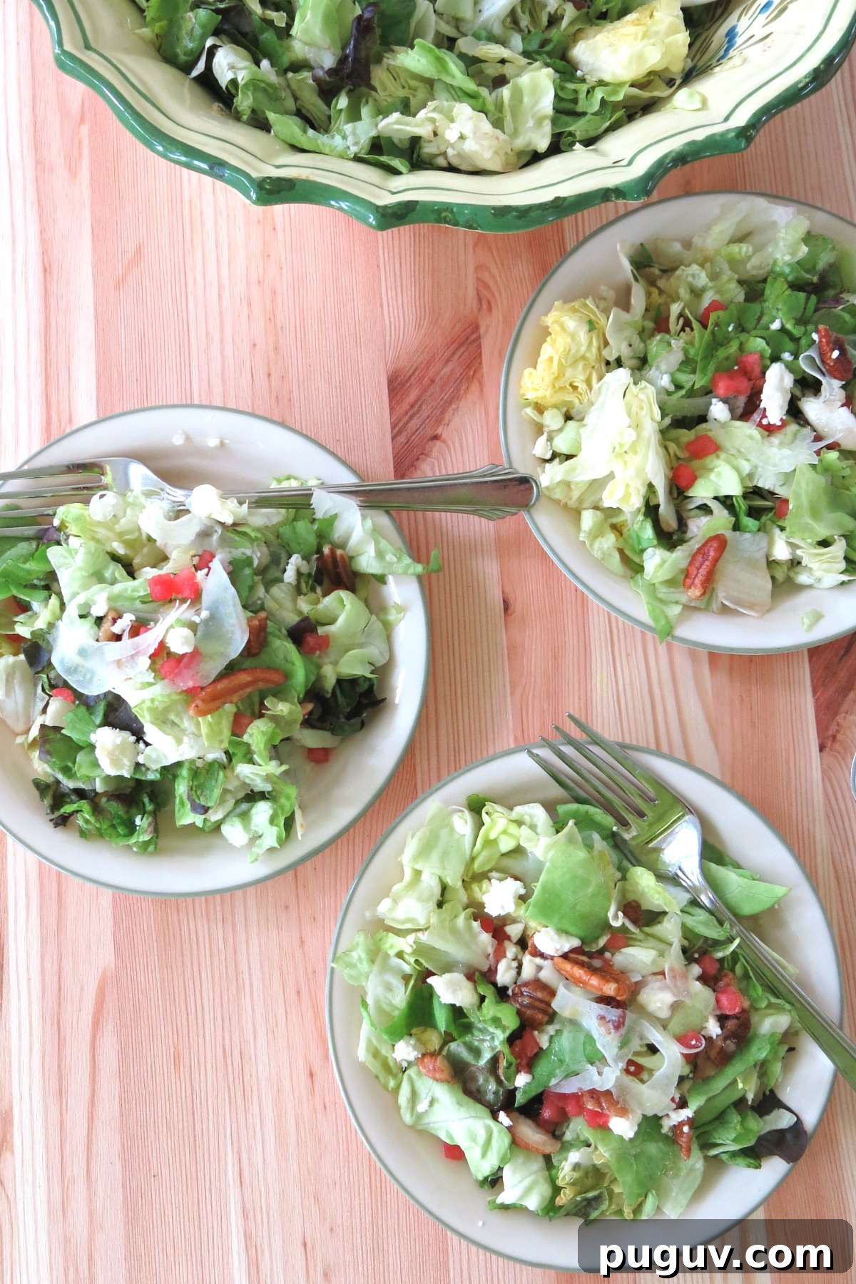 Three small side salads of the fancy salad with shaved fennel, candied pecans, watermelon, and feta cheese on plates with the bowl behind it.