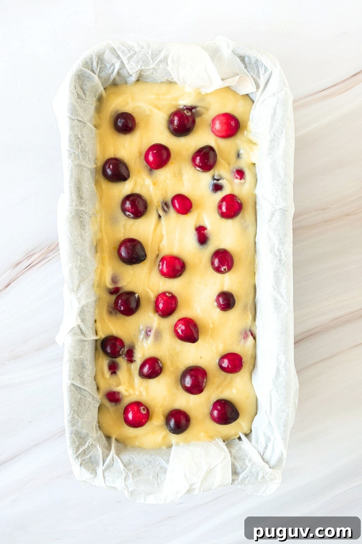 Gluten-Free Cranberry Orange Bread (Dairy-Free) Cranberry bread batter in parchment lined loaf pan.