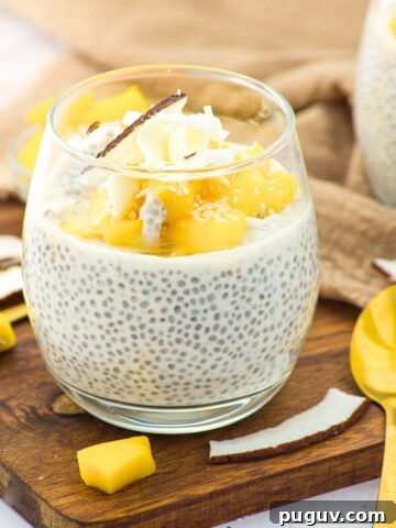 A glass of coconut milk chia pudding topped with fresh mangoes
