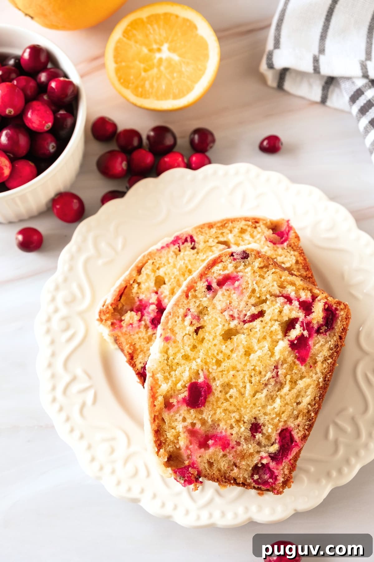 Gluten-Free Orange Cranberry Bread (Dairy-Free) Two slices of gluten-free orange cranberry bread on white plate.