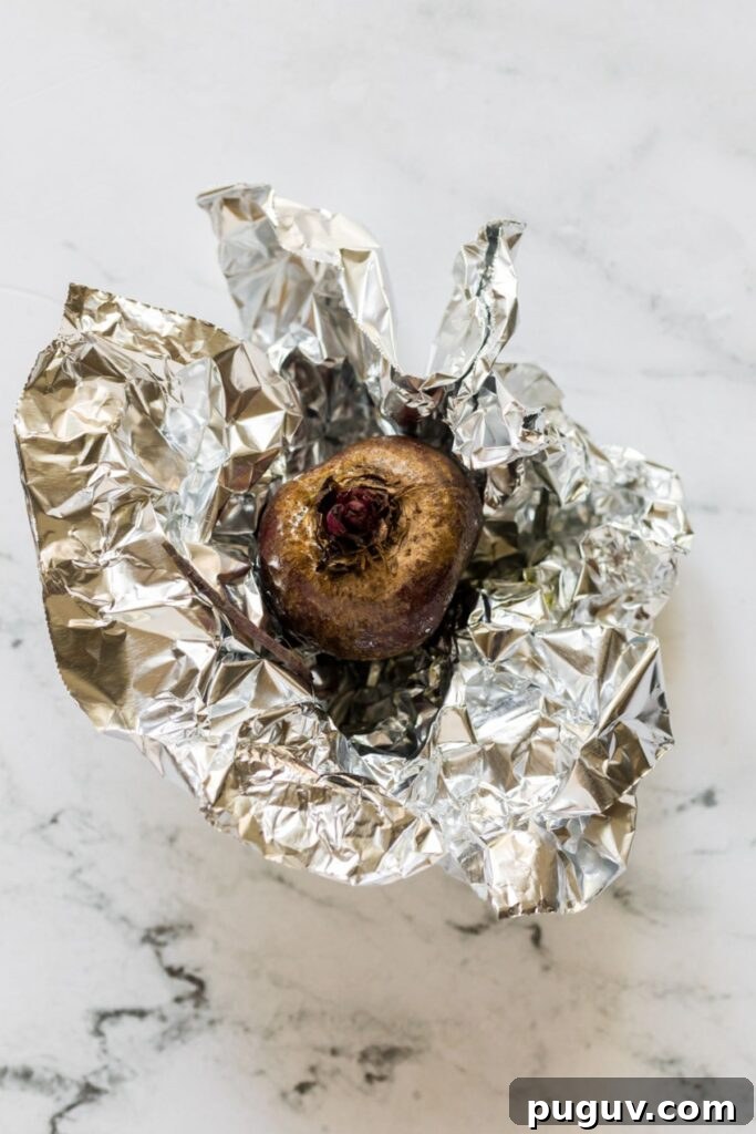 Creamy Beet Hummus Recipe: Vibrant Homemade Dip 4 Roasted beet wrapped in foil on a marble table.