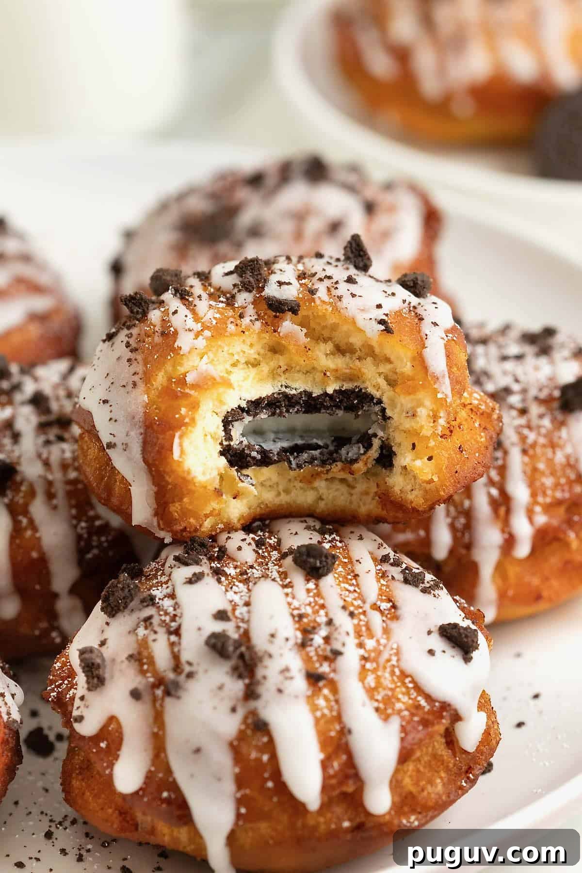 A white rimmed plate holding three fried cinnamon rolls with Oreos in the middle. The one of top is cut open to reveal the Oreo cookie inside.