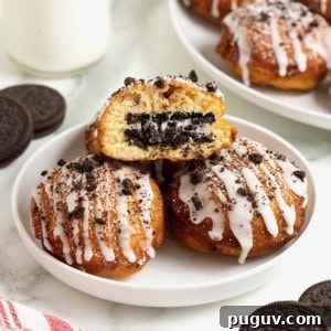 A white rimmed plate holding three fried cinnamon rolls with Oreos in the middle. The one of top is cut open to reveal the Oreo inside.