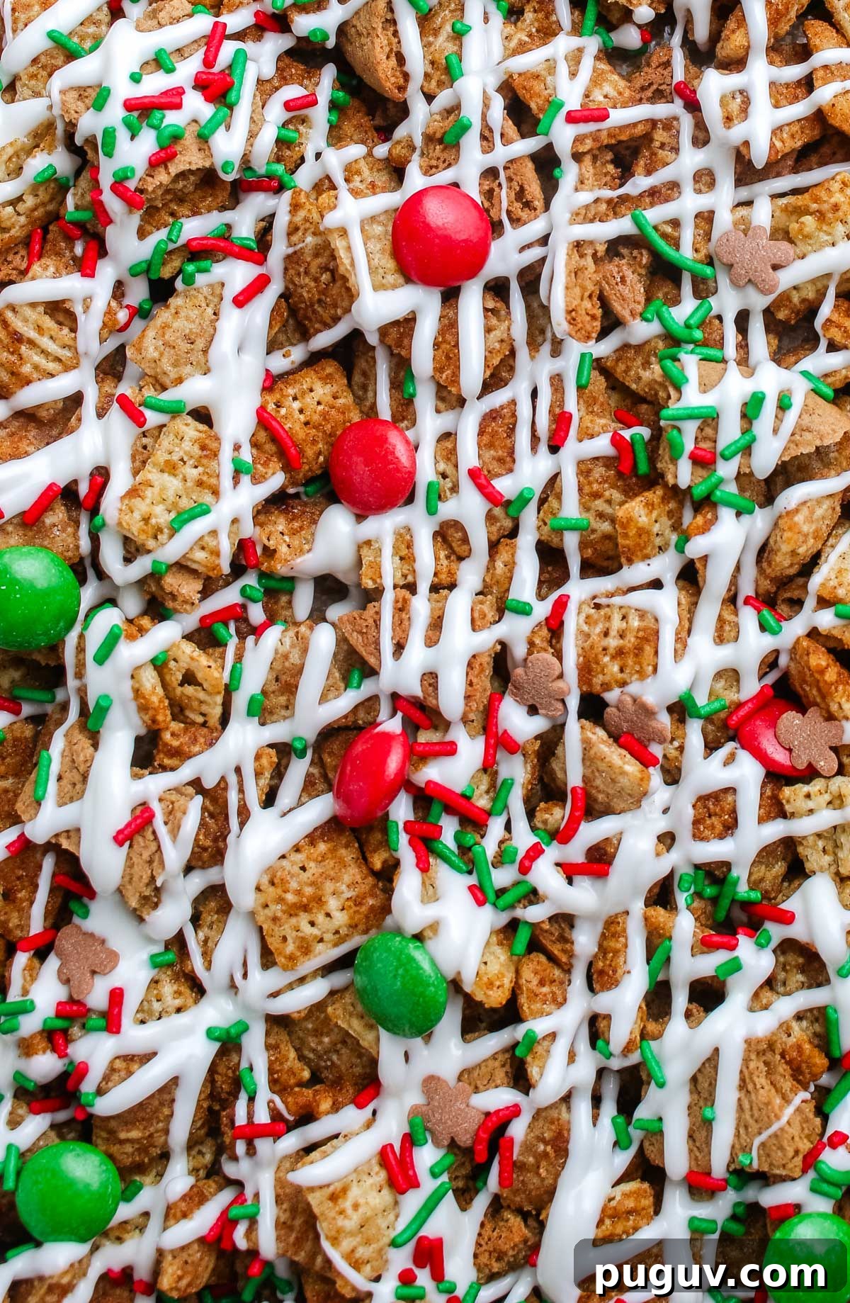 Gingerbread Chex Mix Puppy Chow — Festive Holiday Snack Recipe 2 Macro image of Gingerbread Chex Mix showing texture of cereal coated in white chocolate, red and green candies, and sprinkles.