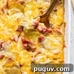 Top down shot of a pan of scalloped ham and potatoes with a spoon sticking out.