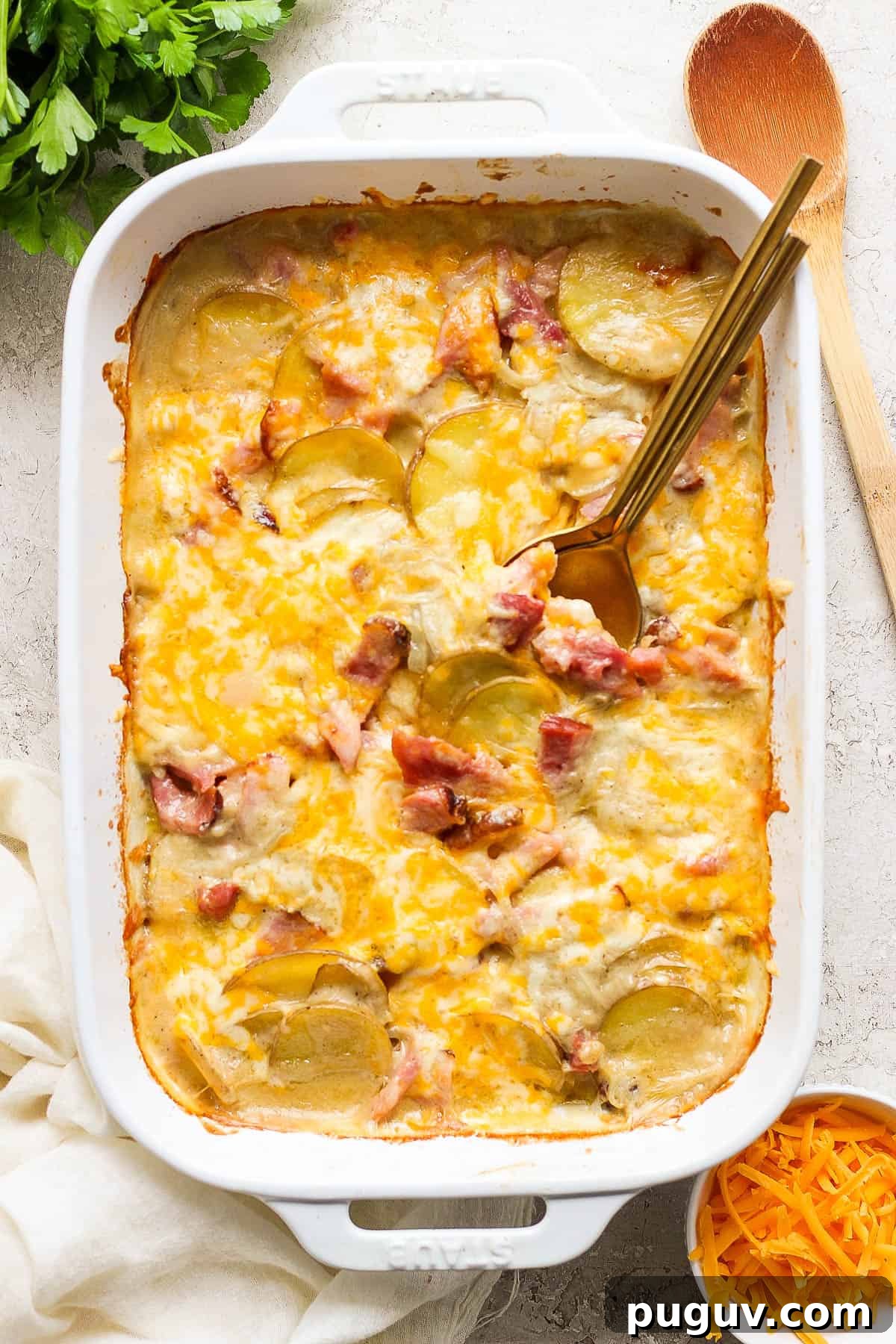 Scalloped potatoes and ham fully cooked in a white baking dish.