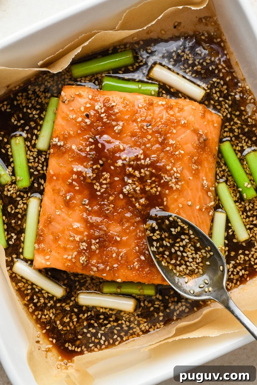30-Minute Garlic-Ginger Glazed Salmon Recipe (Gluten-Free) 12 How to make garlic ginger salmon: A spoon spooning some of the sauce over the salmon filet halfway through baking.