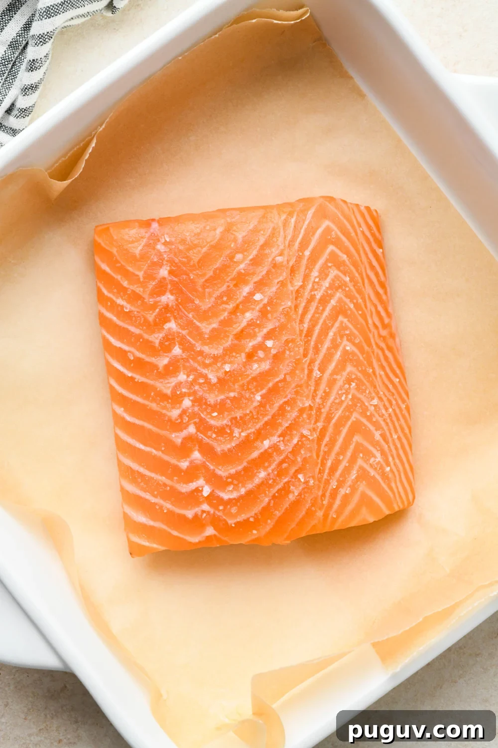 30-Minute Garlic-Ginger Glazed Salmon Recipe (Gluten-Free) 8 How to make garlic ginger salmon: Salted salmon filet in a small white square baking dish lined with parchment paper.