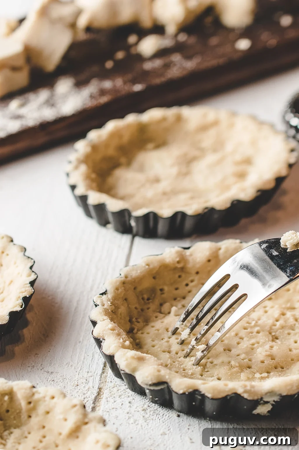 Sugar-Free Butter Tarts: Low-Carb Keto & Gluten-Free Recipe 4 Tart shells filed with an almond flour dough being pricked with a fork.