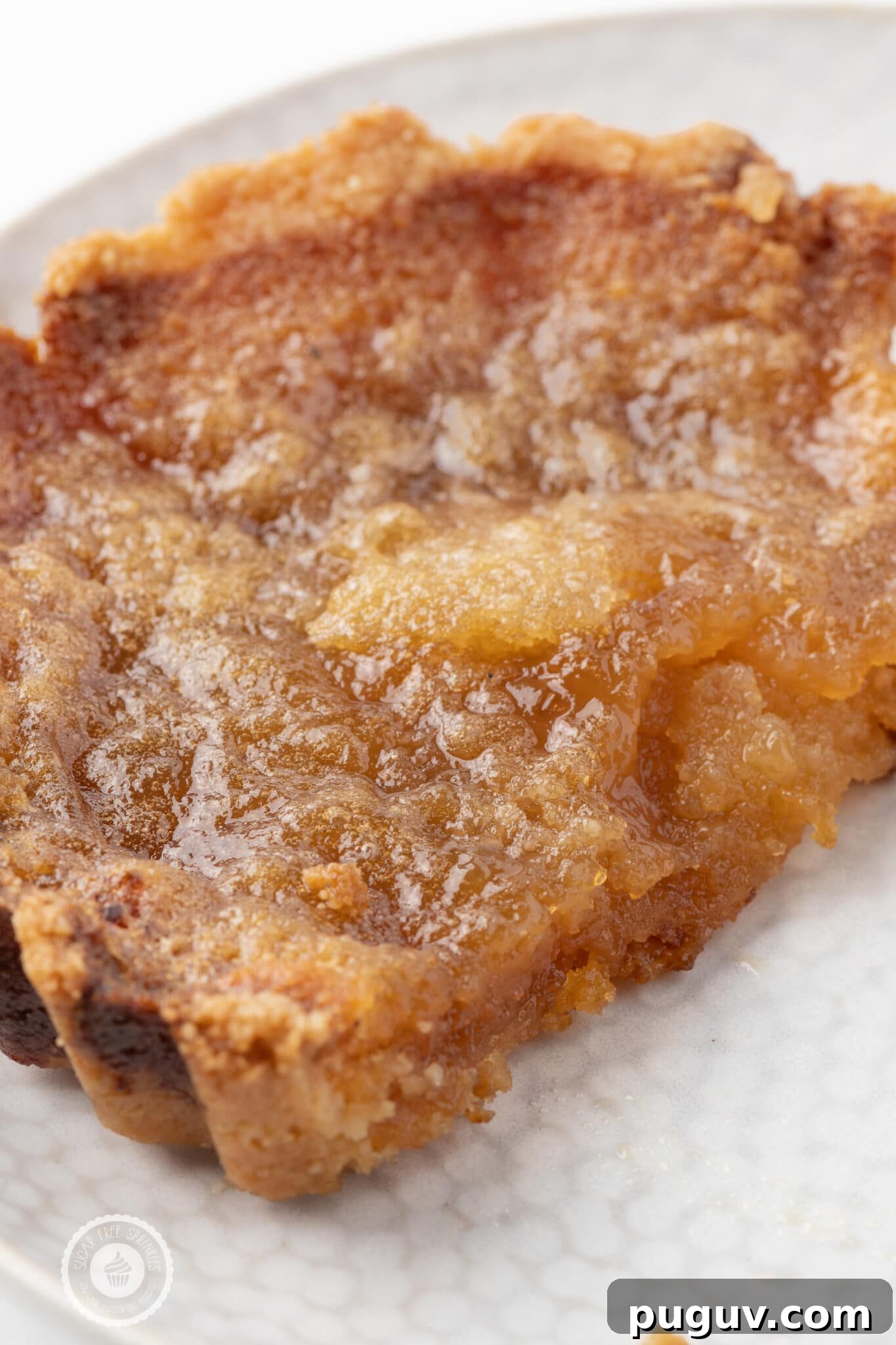 Sugar-Free Butter Tarts: Low-Carb Keto & Gluten-Free Recipe 5 A close of the gooey sticky filling inside of the low carb tarts, The tart is resting on a texture white plate on a bright white table.