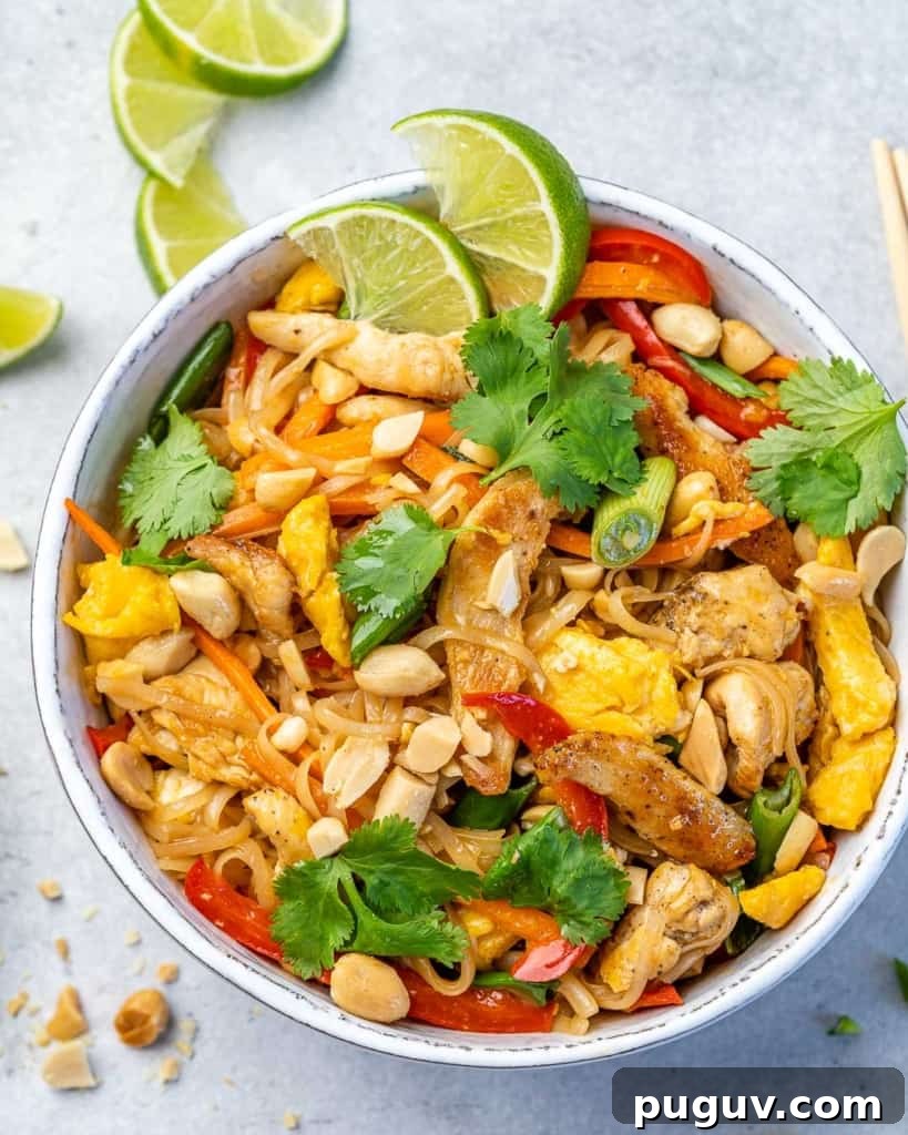 Overhead image of pad thai with chicken in a white bowl.