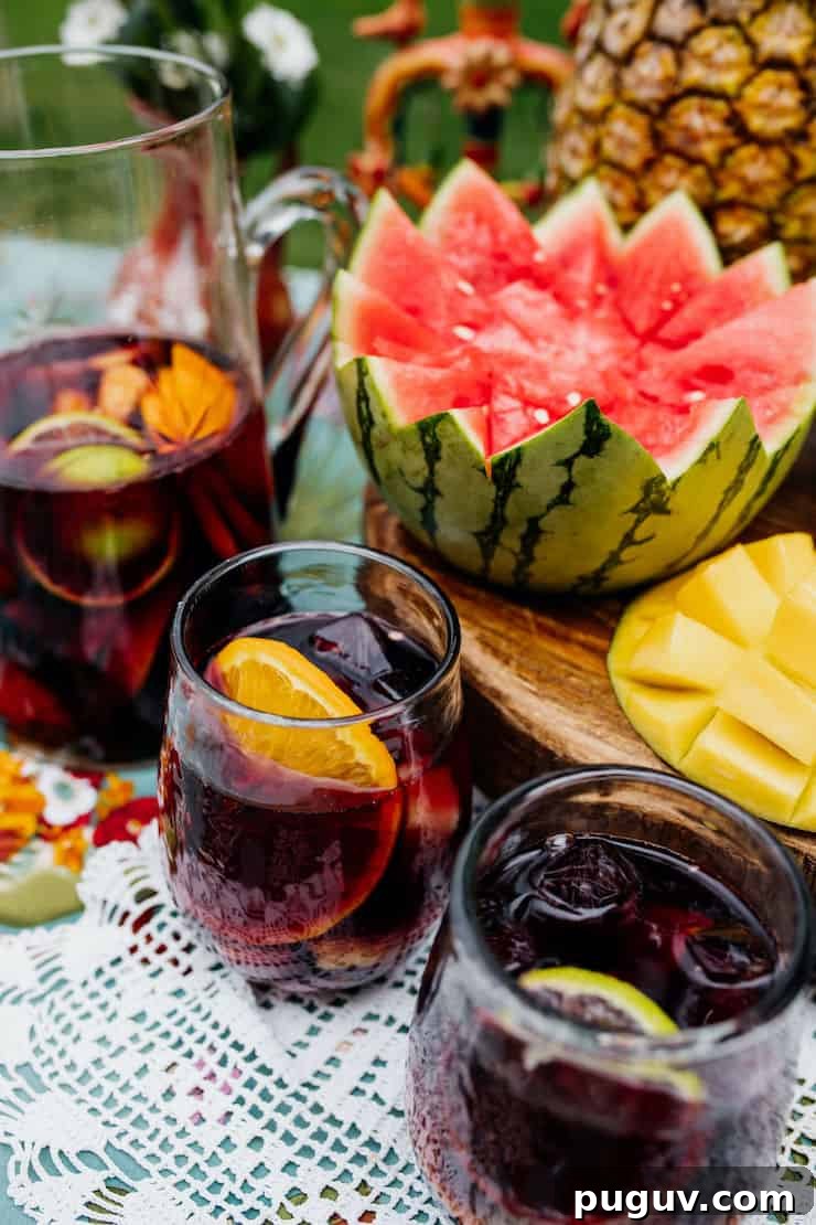 Frida Kahlo-Inspired Sangria Recipe for Parties 3 two glass and a pitcher filled with sangria and a carved watermelon inspired by Frida still life painting