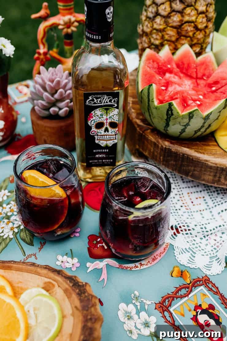 Frida Kahlo-Inspired Sangria Recipe for Parties 6 tequila infused sangria recipe in two glasses with a bottle of Exotico tequila in the background