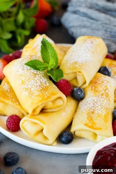 Cheese blintzes garnished with powdered sugar and berries.