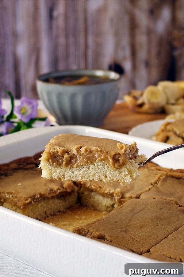 Decadent Bananas Foster Butter Cake Recipe for Dessert Fans 3 Someone using a spatula to lift a piece of St. Louis Gooey Butter Cake from a baking dish.