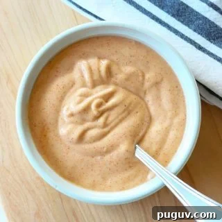 Creamy Yum Yum Sauce Recipe: Simple Homemade Japanese Steakhouse Sauce 7 A white bowl of yum yum sauce with a spoon in it for serving.