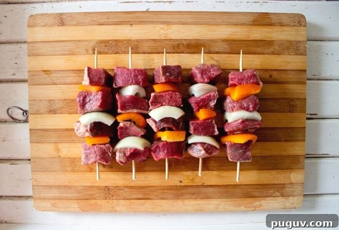 raw lamb sosaties on chopping board prepared with bell peppers and onions