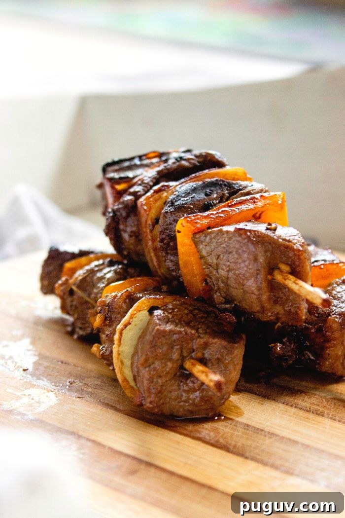 closeup of grilled lamb sosaties with bell pepper and onions on chopping block
