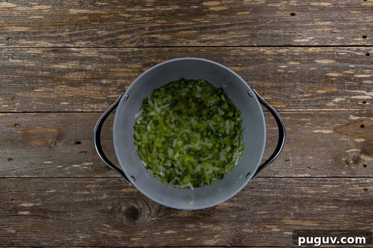 Chopped onion, bell pepper, and celery cooking in a pot with butter,