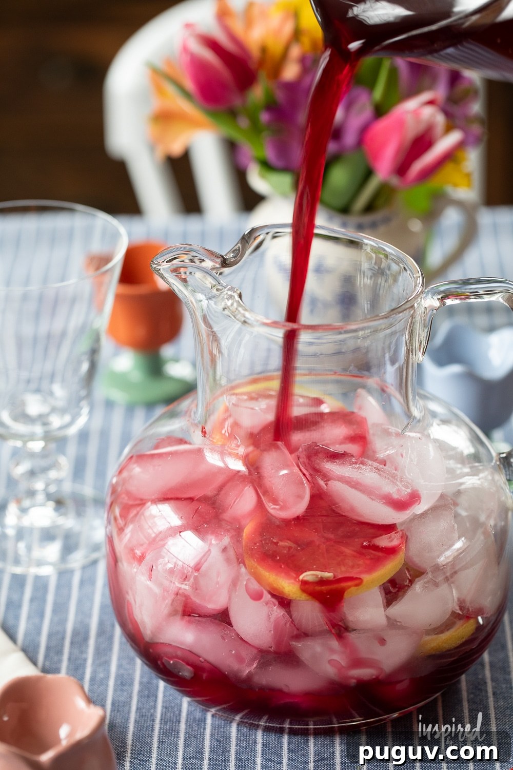 Pink Tulip Cocktail Recipe: Floral Vodka Drink Guide 7 pouring cranberry juice into a pitcher with ice.