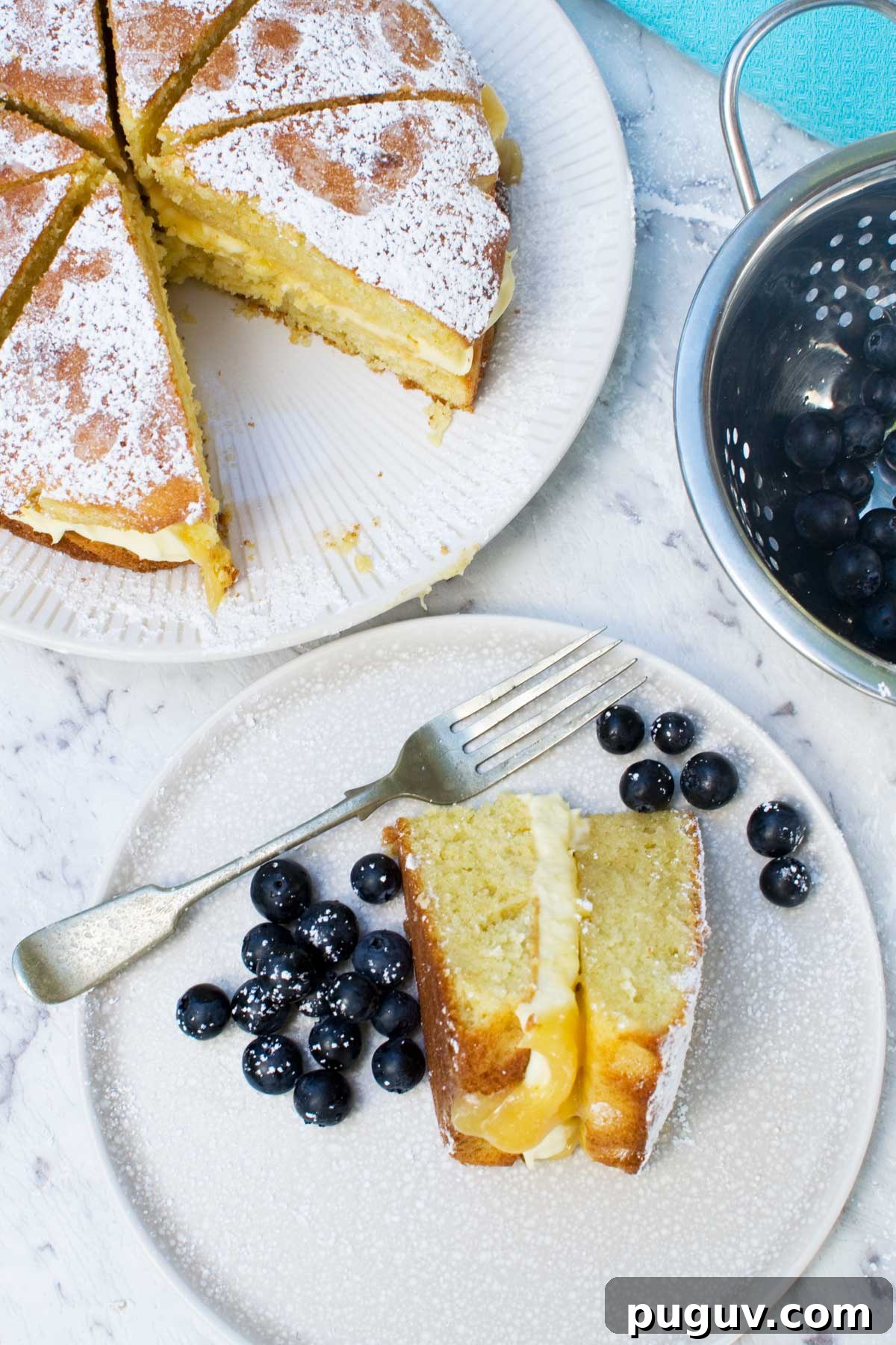 Lemon Mascarpone Cake Recipe with Zesty Glaze 6 A slice of lemon mascarpone cake on a plate and the rest of the cake on a white plate on a marble background from above