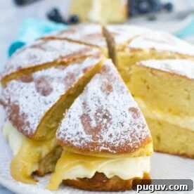 Lemon Mascarpone Cake Recipe with Zesty Glaze 7 A whole lemon mascarpone cake sliced on a white plate