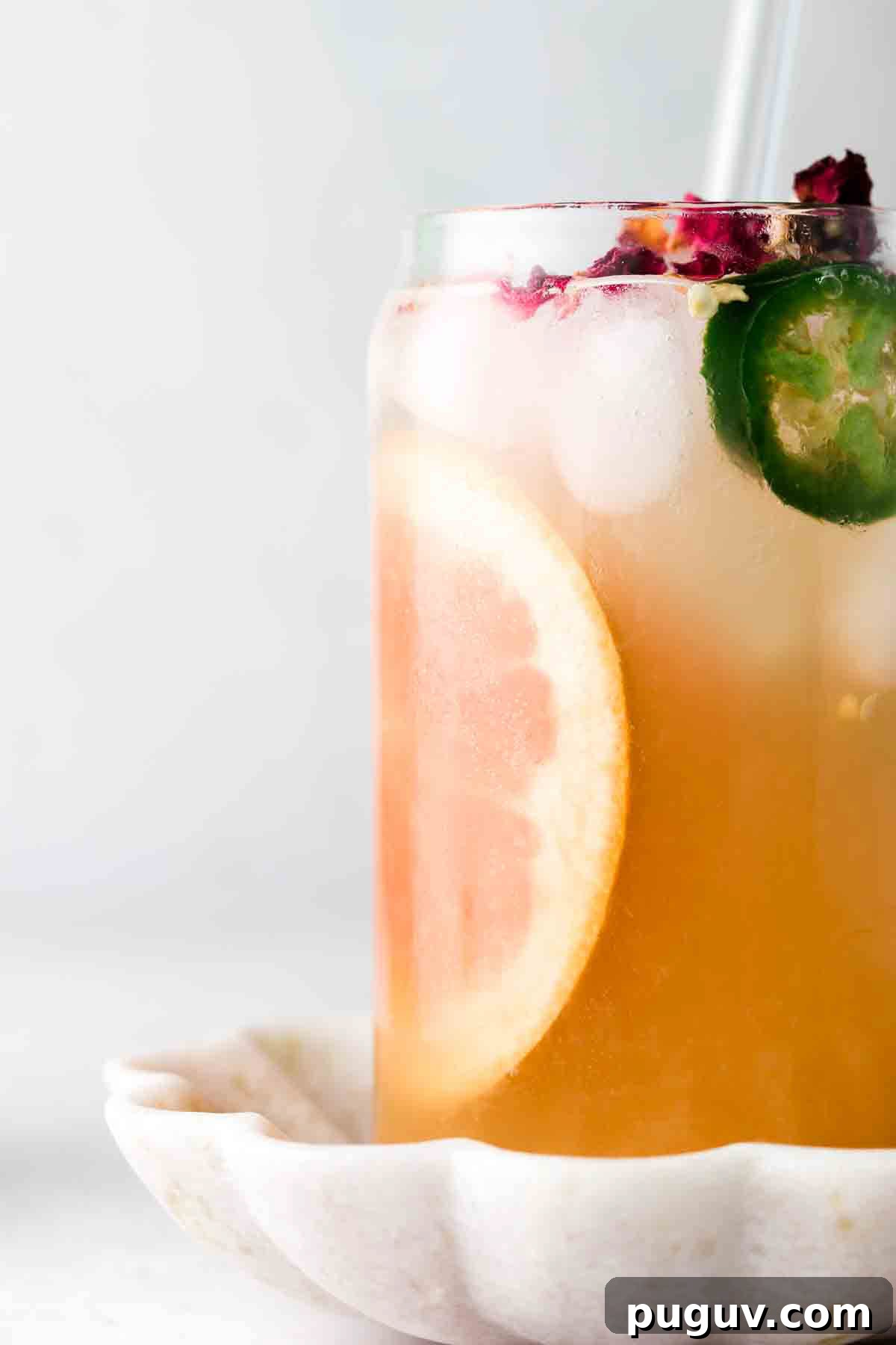 Grapefruit juice in a glass with a jalapeno on top.