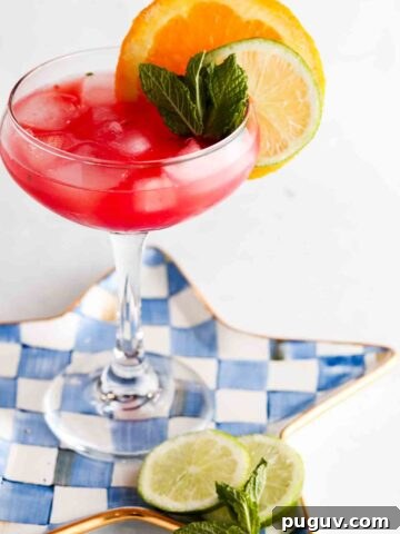 Watermelon mocktail margarita in a margarita glass with a lime and orange on top.