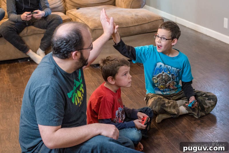 How a Gaming Console Can Bring Your Family Together 8 a father and a son high-fiving over a boy concentrating on a game