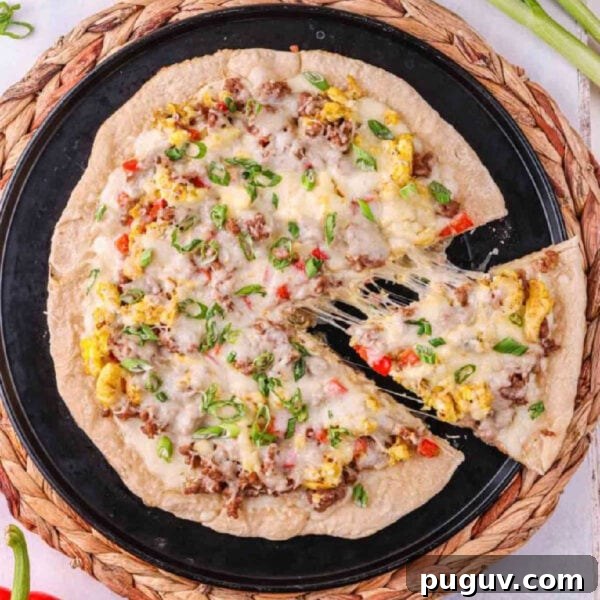 A pizza with cheese, meat and vegetables on a black plate.