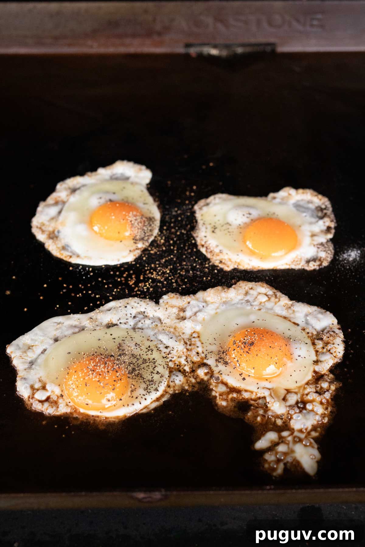 Fried eggs cooked on the griddle topped with seasoning