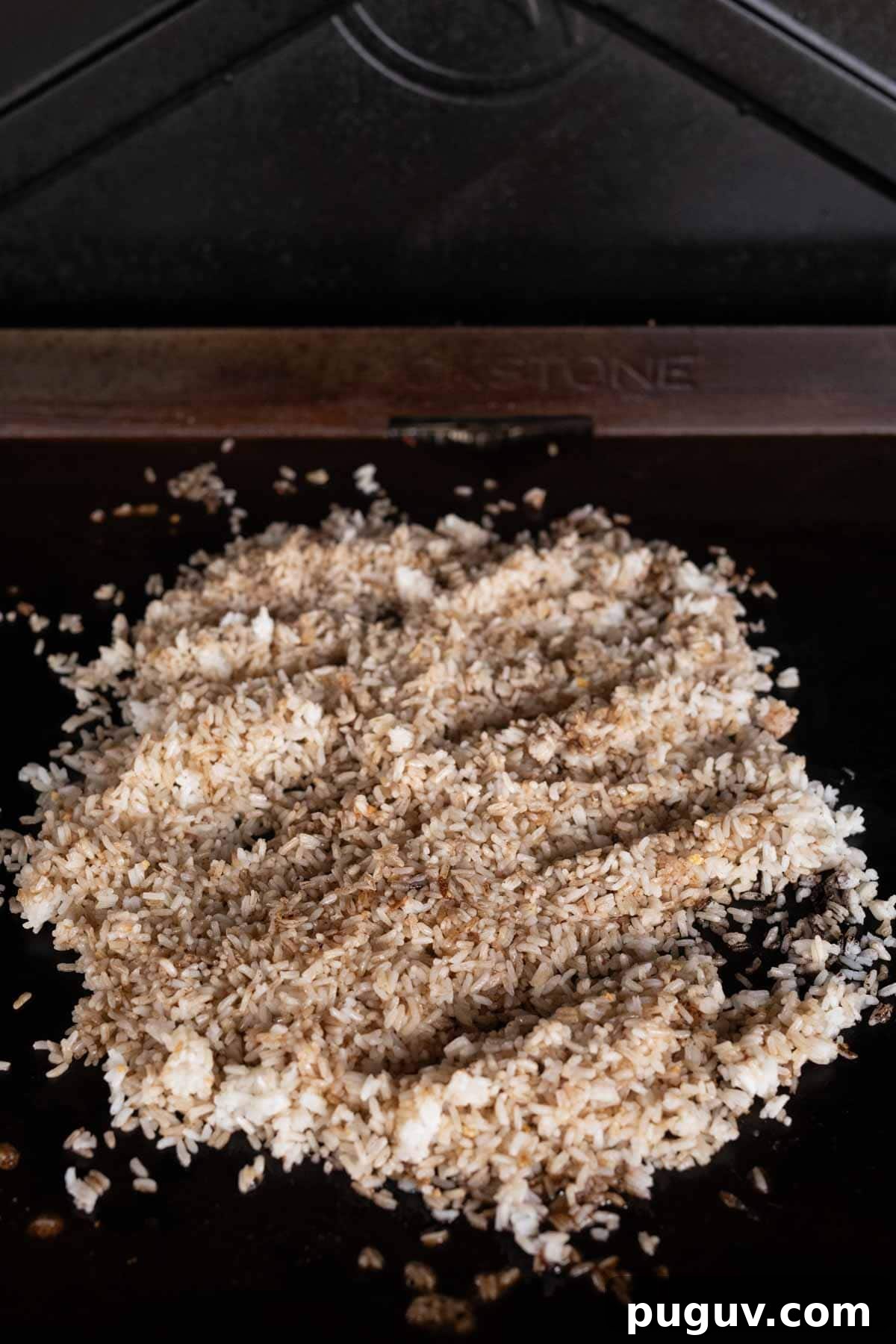 Cooked rice topped with sauce and seasoning on the griddle