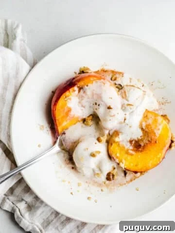 Peach halves in a bowl with ice cream and walnuts.