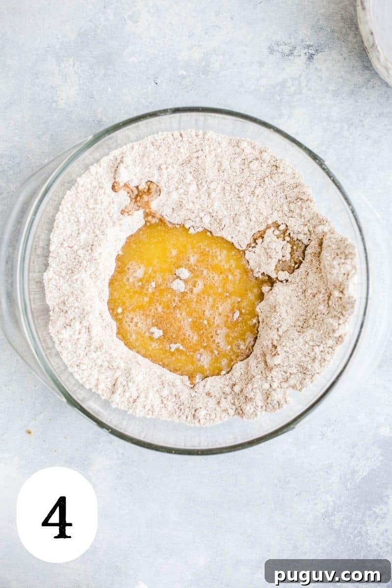 Gluten-Free Peach Oat Crumble Recipe for Summer Desserts 7 Oat flour mixture with melted vegan butter in a glass mixing bowl.