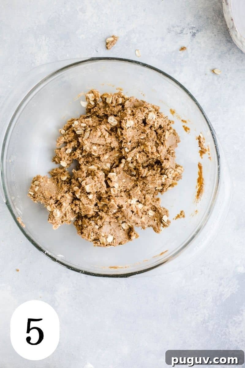 Gluten-Free Peach Oat Crumble Recipe for Summer Desserts 8 Oat flour and oats mixed into a dough with coconut oil and maple syrup in a glass mixing bowl.