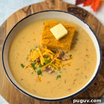 Creamy Bacon and Beer Cheese Soup Recipe 11 beer cheese soup with bacon, shredded cheese, green onions, and a slice of sweet potato cornbread in a white bowl