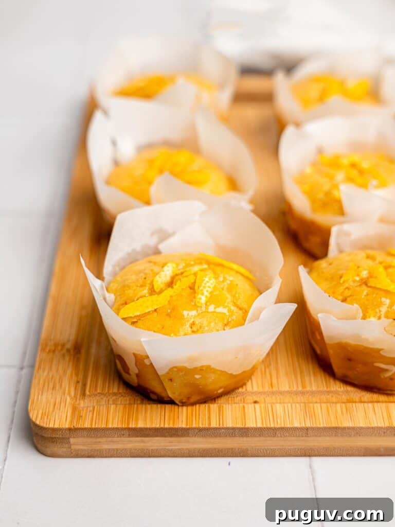 Lemon Drizzle Muffins That Actually Taste Indulgent 2 Healthy Lemon Muffins on a wooden board.
