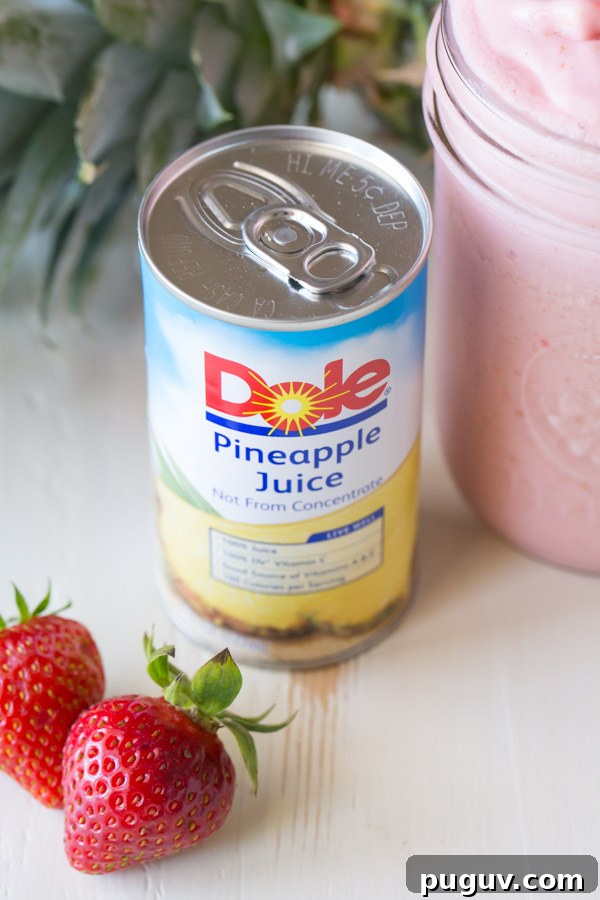 Pineapple Strawberry Cream Slush Recipe — Refreshing Tropical Drink 4 A can of Dole Pineapple Juice, next to a glass jar of Dole Pineapple Strawberry Cream Slush and some whole strawberries.