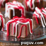 Side shot of chocolate raspberry fudge pieces on a clear plate.