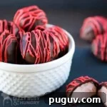 Close up shot of strawberry cream truffles in a white bowl with a truffle split in half in the front.