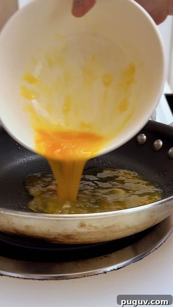 15-Minute Egg & Cheese Breakfast Quesadilla Recipe 4 pouring eggs into pan to cook
