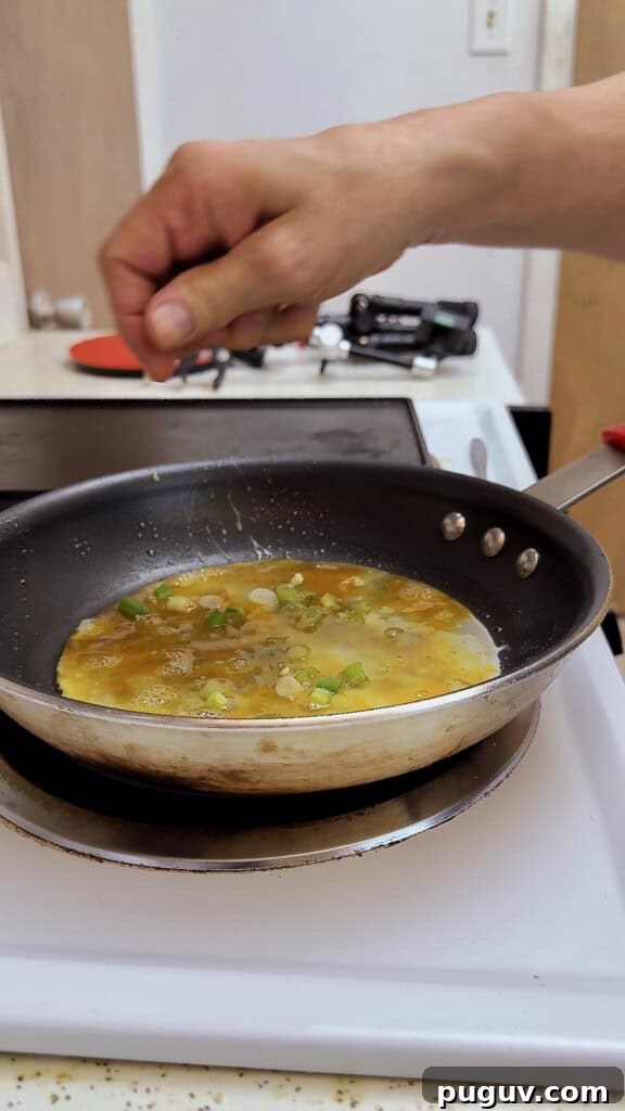 15-Minute Egg & Cheese Breakfast Quesadilla Recipe 5 adding green onions to eggs