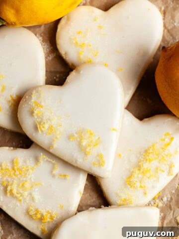 gluten free lemon sugar cookies topped with lemon glaze and lemon sugar on brown parchment paper
