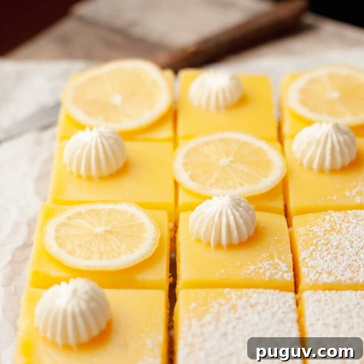 gluten free lemon bars with a shortbread crust topped with powdered sugar, whipped cream and slices of lemons on parchment paper