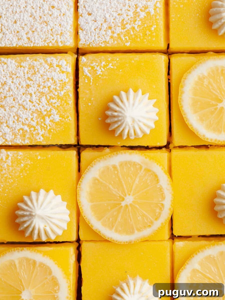 Gluten-Free Lemon Bars Recipe with Tangy Shortbread Crust 8 gluten free lemon squares topped with powdered sugar, whipped cream and slices of lemons on parchment paper