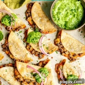 A metal sheet pan with crispy bean and cheese tacos.