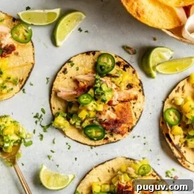 Grey tabletop with three salmon tacos.